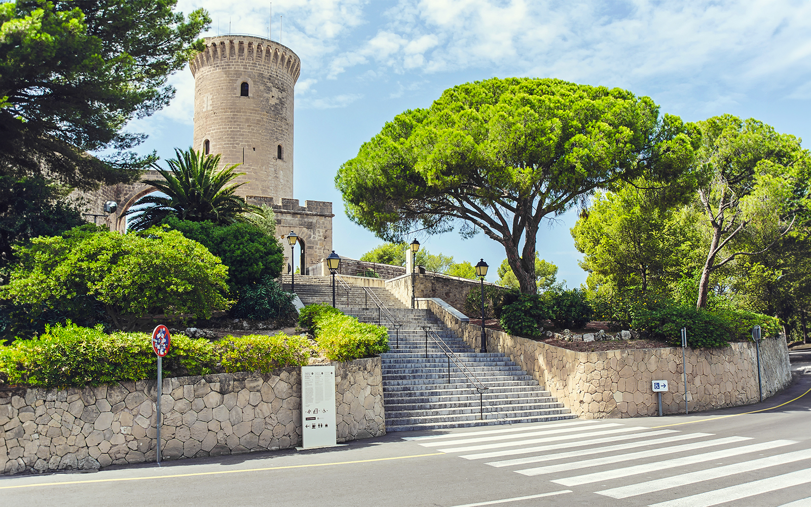 Bellver Castle in Palma de Mallorca with circular towers and surrounding forest.