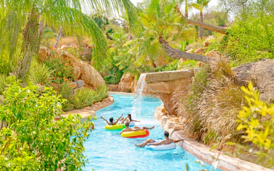Lazy river with people on floats at Zoomarine Algarve surrounded by lush greenery.