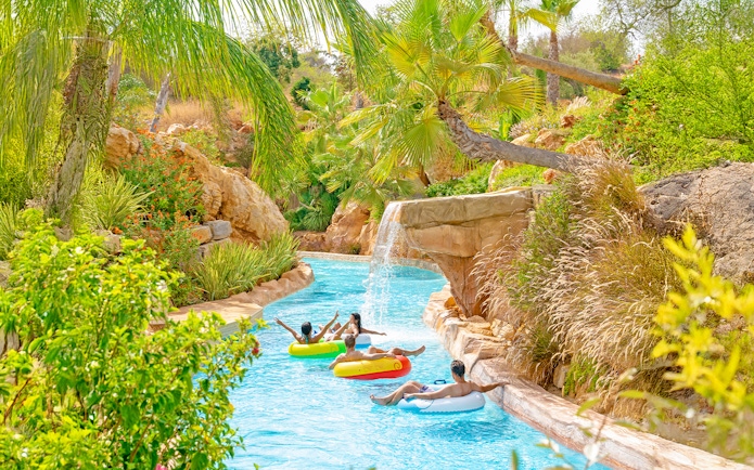 Lazy river with people on floats at Zoomarine Algarve surrounded by lush greenery.