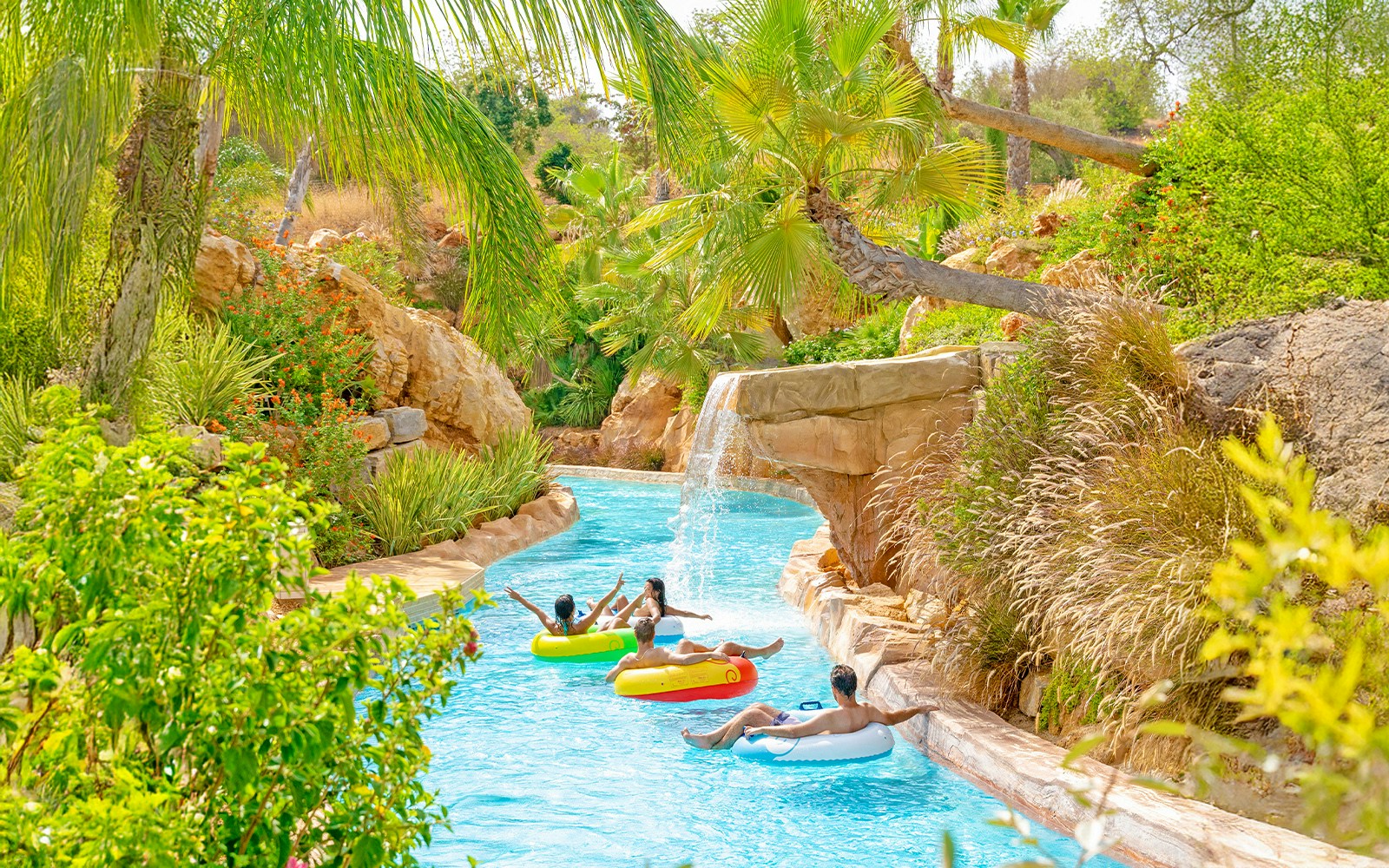 Visitors floating on the lazy river at Zoomarine Algarve, surrounded by lush greenery and water attractions.