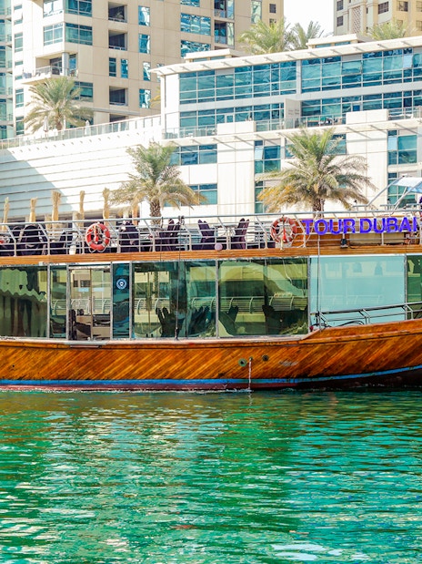 Dhow cruise on Dubai Creek with cityscape backdrop.