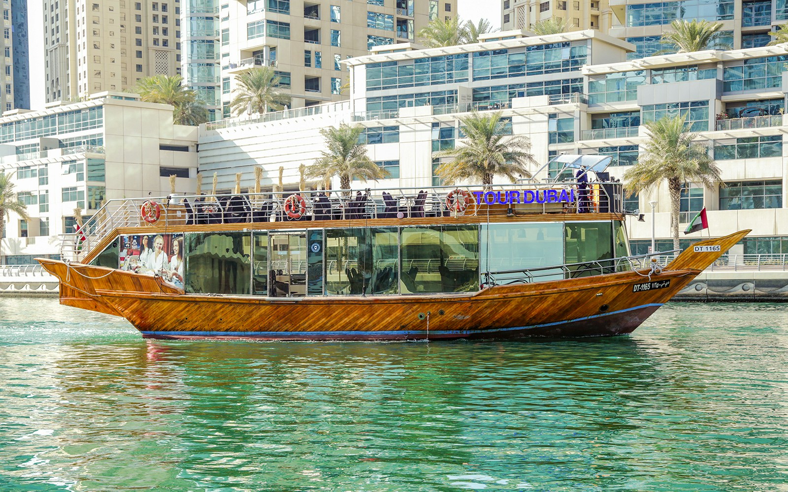 Dhow cruise on Dubai Creek with city skyline in the background, offering sightseeing and unlimited soft drinks.