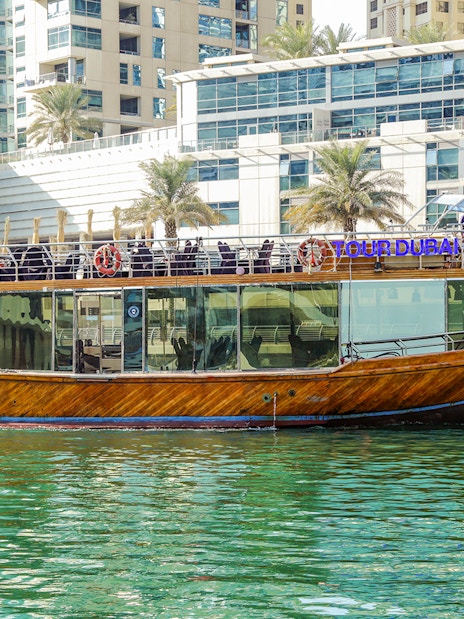 Dhow cruise on Dubai Creek with cityscape backdrop.