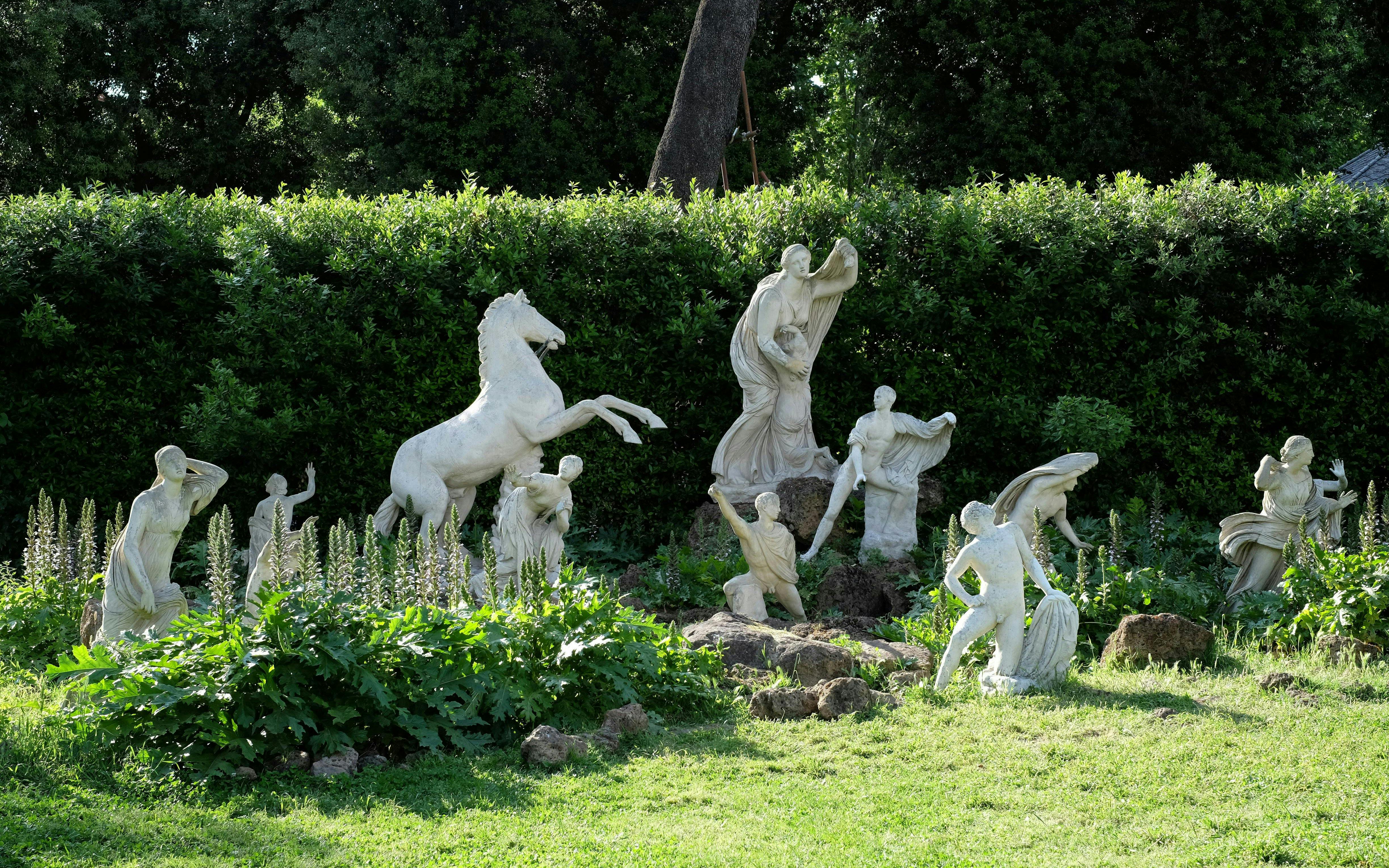 Statues in the garden of Villa Medici, Rome, surrounded by greenery.