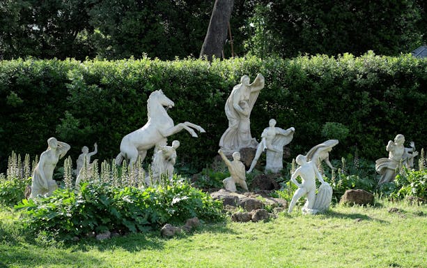 Statues in the garden of Villa Medici, Rome, surrounded by greenery.