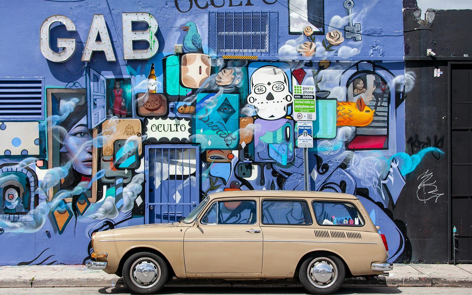 Mural and graffiti art on Wynwood Walls, Miami, featuring vibrant designs and a parked vintage car.