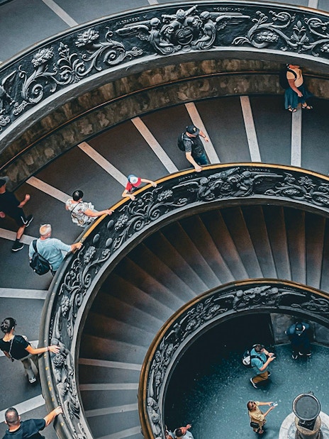 Vatican Museum spiral staircase with visitors, part of private tour experience.