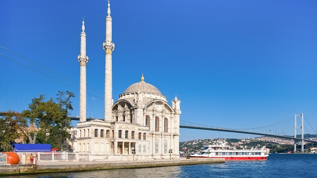 Ortakoy Mosque by Bosphorus with cruise boat, Istanbul, Turkey.
