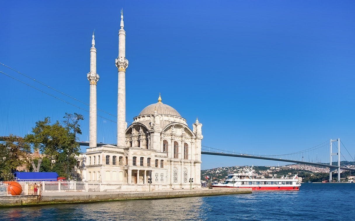 Ortakoy Mosque by Bosphorus with cruise boat, Istanbul, Turkey.