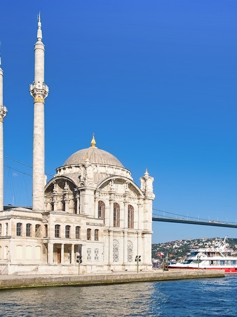 Ortakoy Mosque by Bosphorus with cruise boat, Istanbul, Turkey.