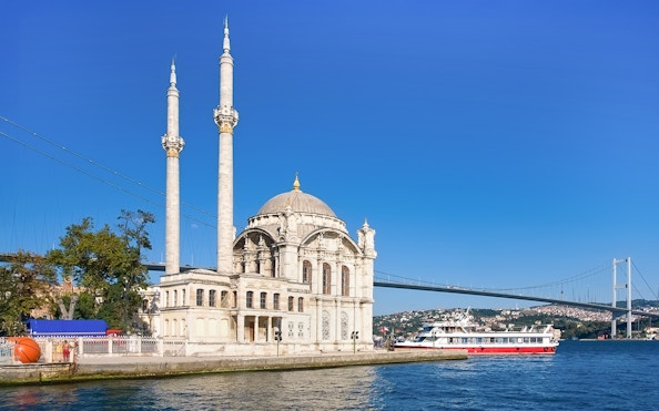 Ortakoy Mosque by Bosphorus with cruise boat, Istanbul, Turkey.