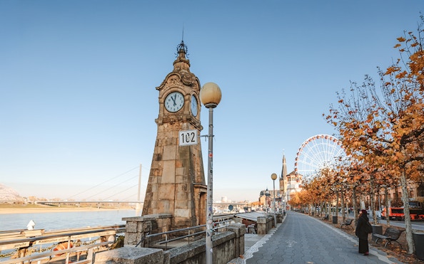 Clock tower and promenade in Dusseldorf Old Town with Ferris wheel in the background.