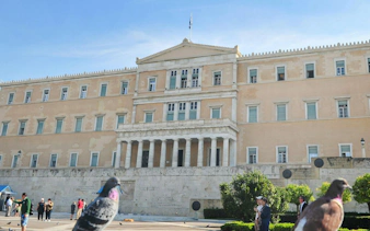 Hellenic Parliament building with tourists and pigeons in Athens.