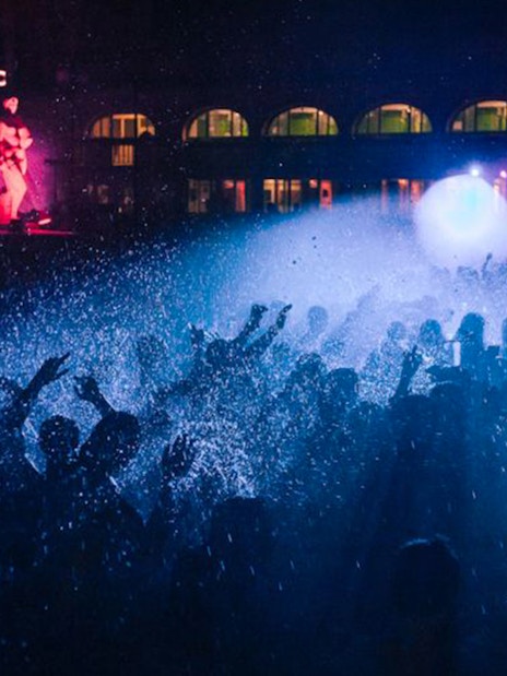 Crowd enjoying a vibrant night concert with colorful lights and water effects.