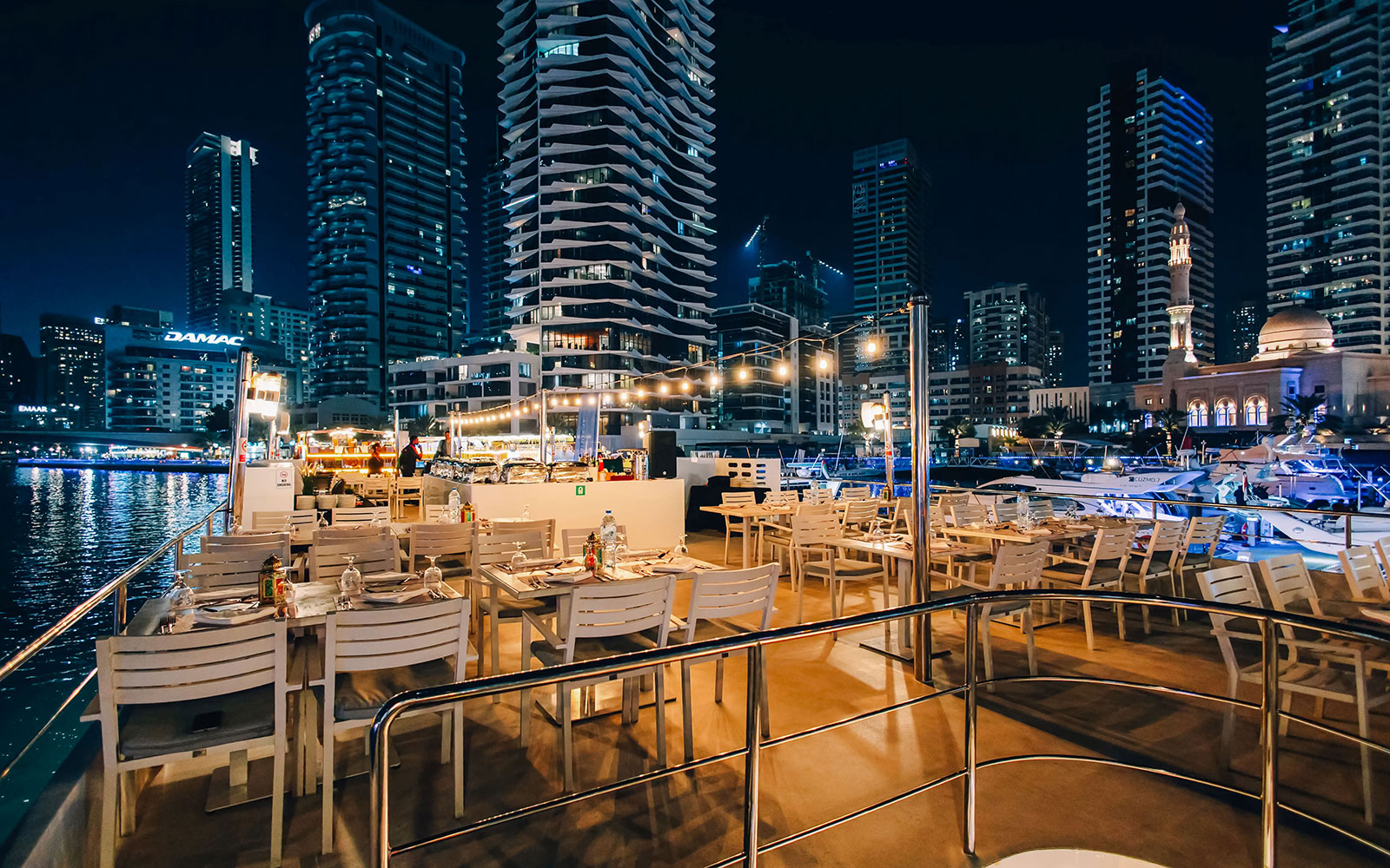 Seating area on Alexandra Sea Lounge Dhow Cruise with city skyline at night.