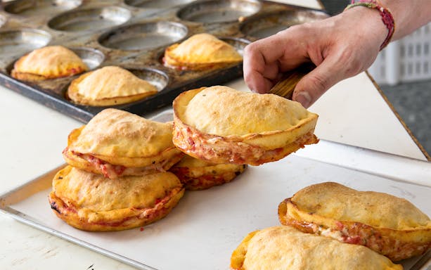 Hand holding freshly baked focaccia during street food tour in Polignano a Mare.