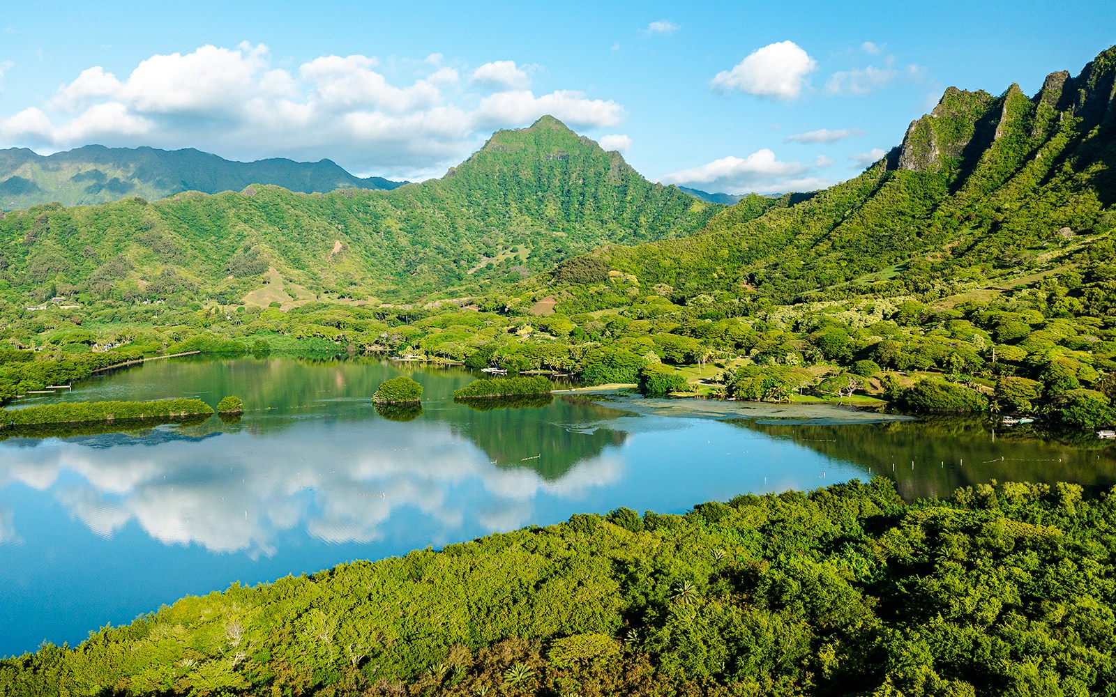 Lush green mountains and a reflective lake at Kualoa Ranch, Hawaii.