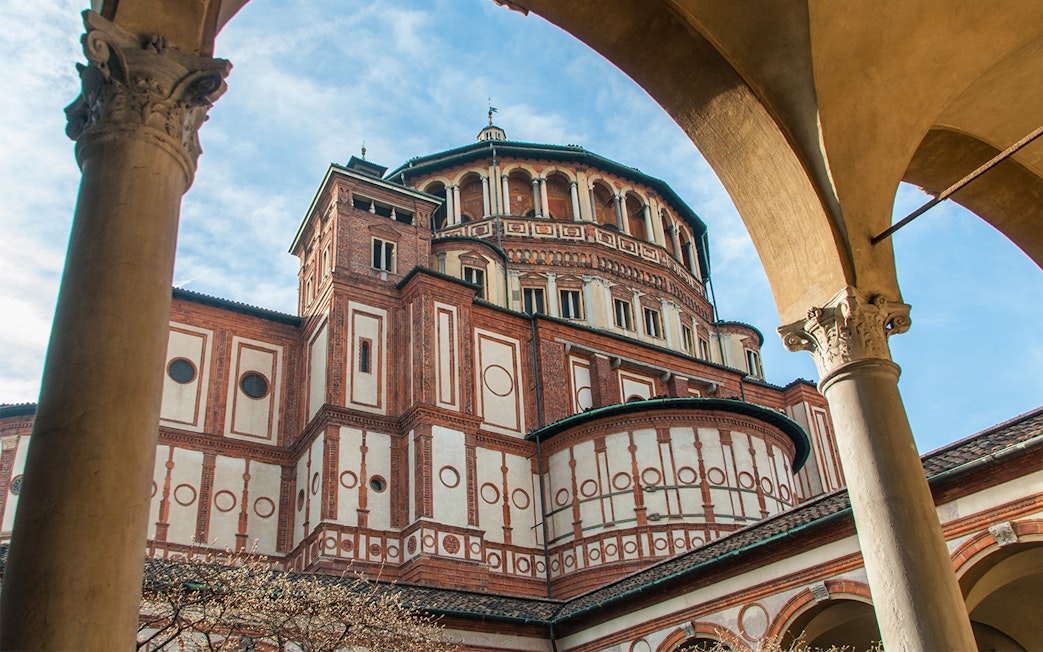 Santa Maria delle Grazie church exterior in Milan, Italy, viewed through archway.
