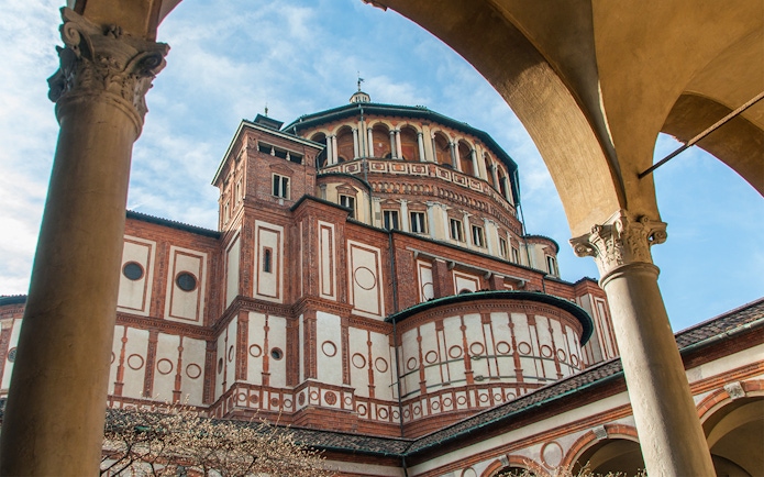 Santa Maria delle Grazie church exterior in Milan, Italy, viewed through archway.
