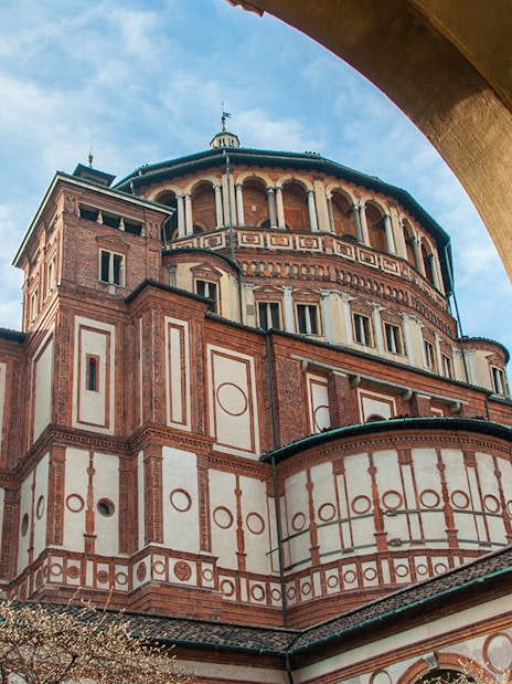 Santa Maria delle Grazie church exterior in Milan, Italy, viewed through archway.