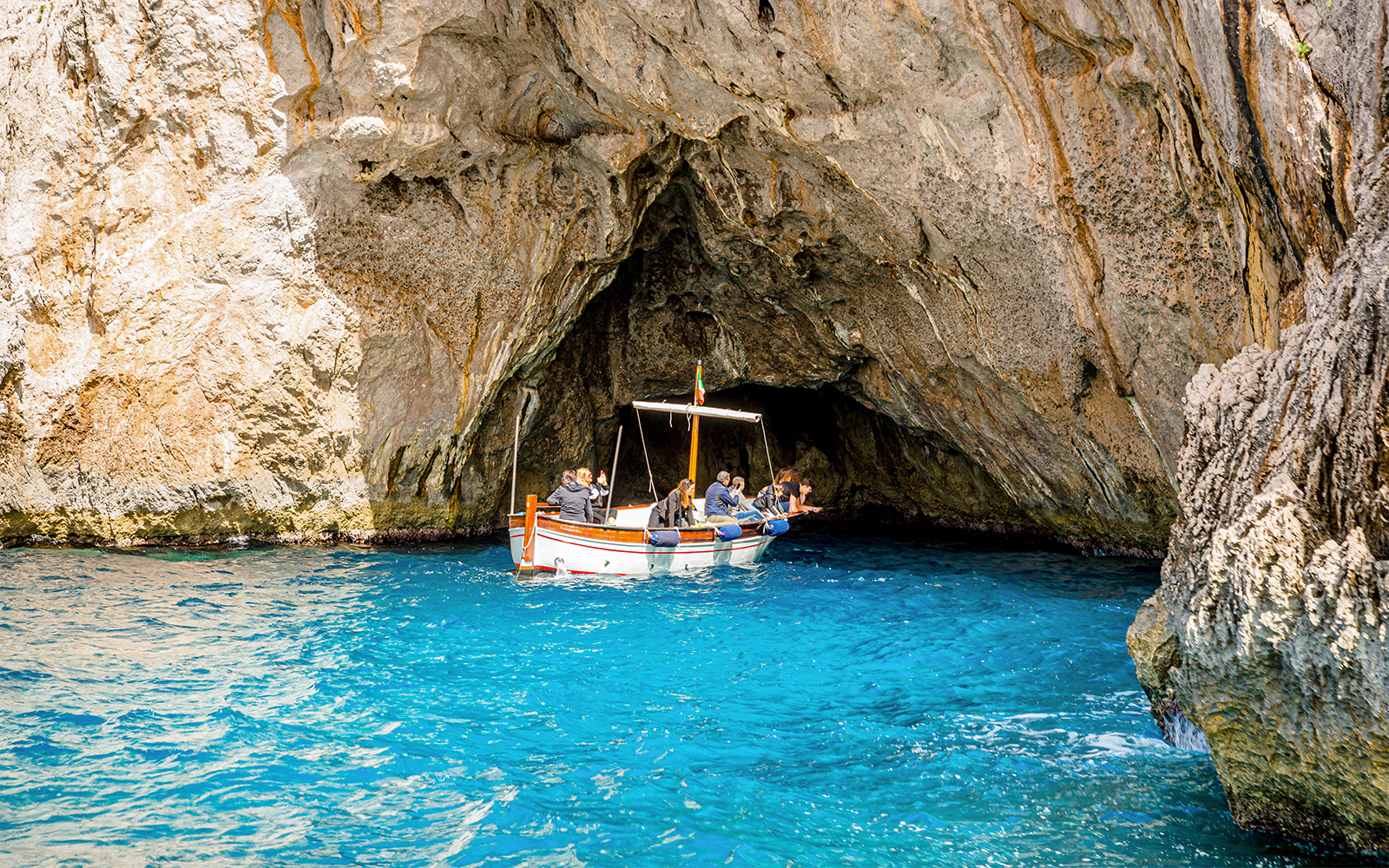 Boat entering Blue Grotto cave on Capri tour from Rome.