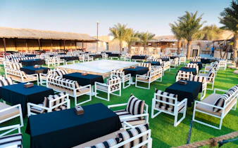 Outdoor seating area with striped cushions and tables set for a Dubai desert safari experience.