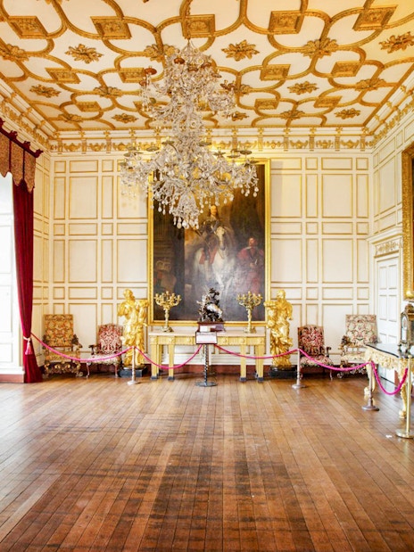 Warwick Castle interior with ornate paintings and chandelier.