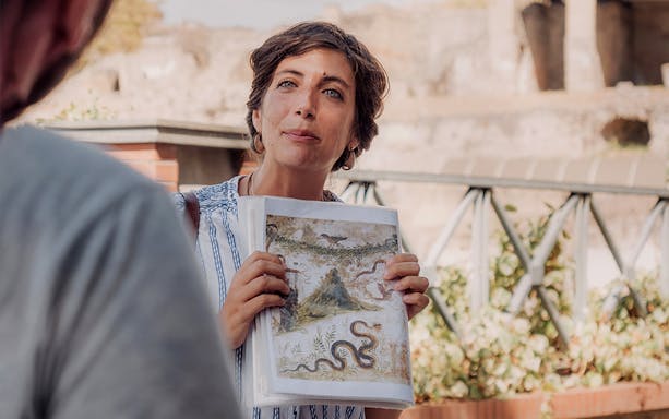 Tour guide showing ancient fresco during Pompeii and Oplontis small group tour.