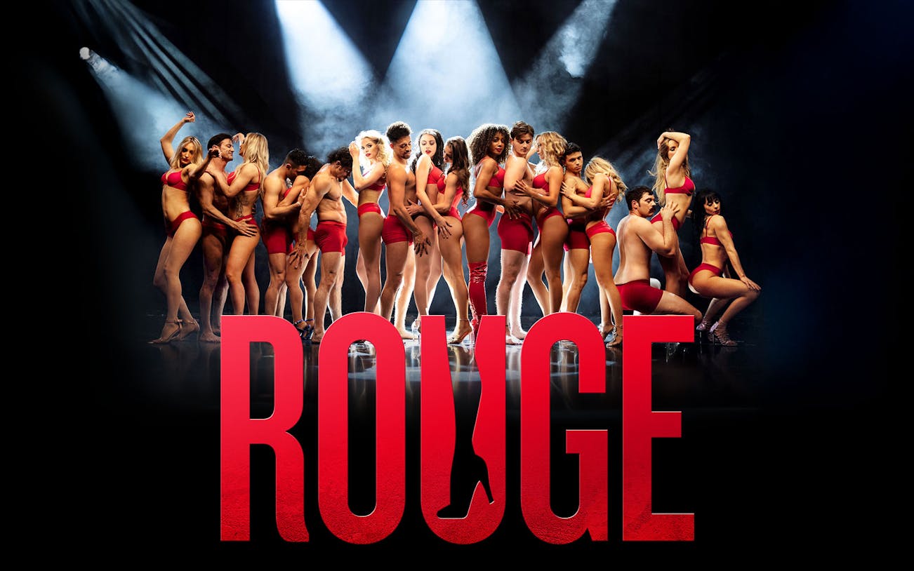 Performers in red outfits on stage with "Rouge" in bold letters.
