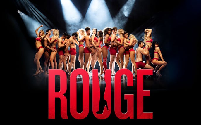 Performers in red outfits on stage with "Rouge" in bold letters.