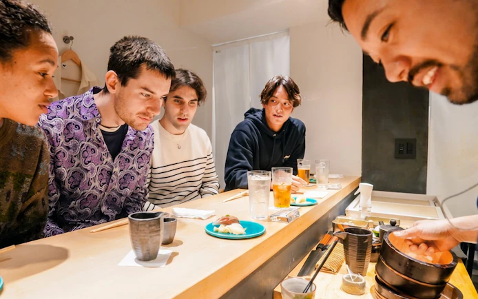 Group enjoying sushi and A5 Wagyu at a Tokyo omakase counter in Shinjuku.