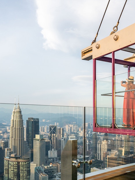 Tourist photographing cityscape from Kuala Lumpur Tower Glass Box.