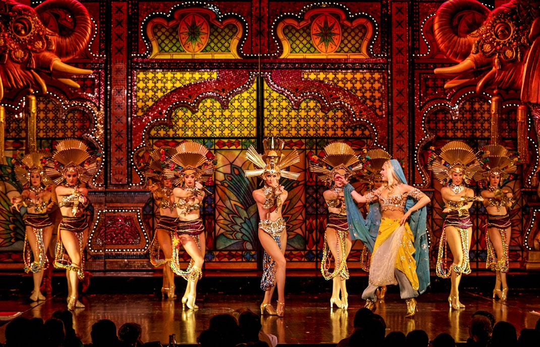 Moulin Rouge cabaret performance with dinner in Paris, featuring vibrant costumes and dancers.