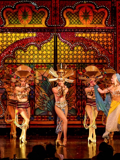 Performers in elaborate costumes on stage at the Moulin Rouge Show in Paris.