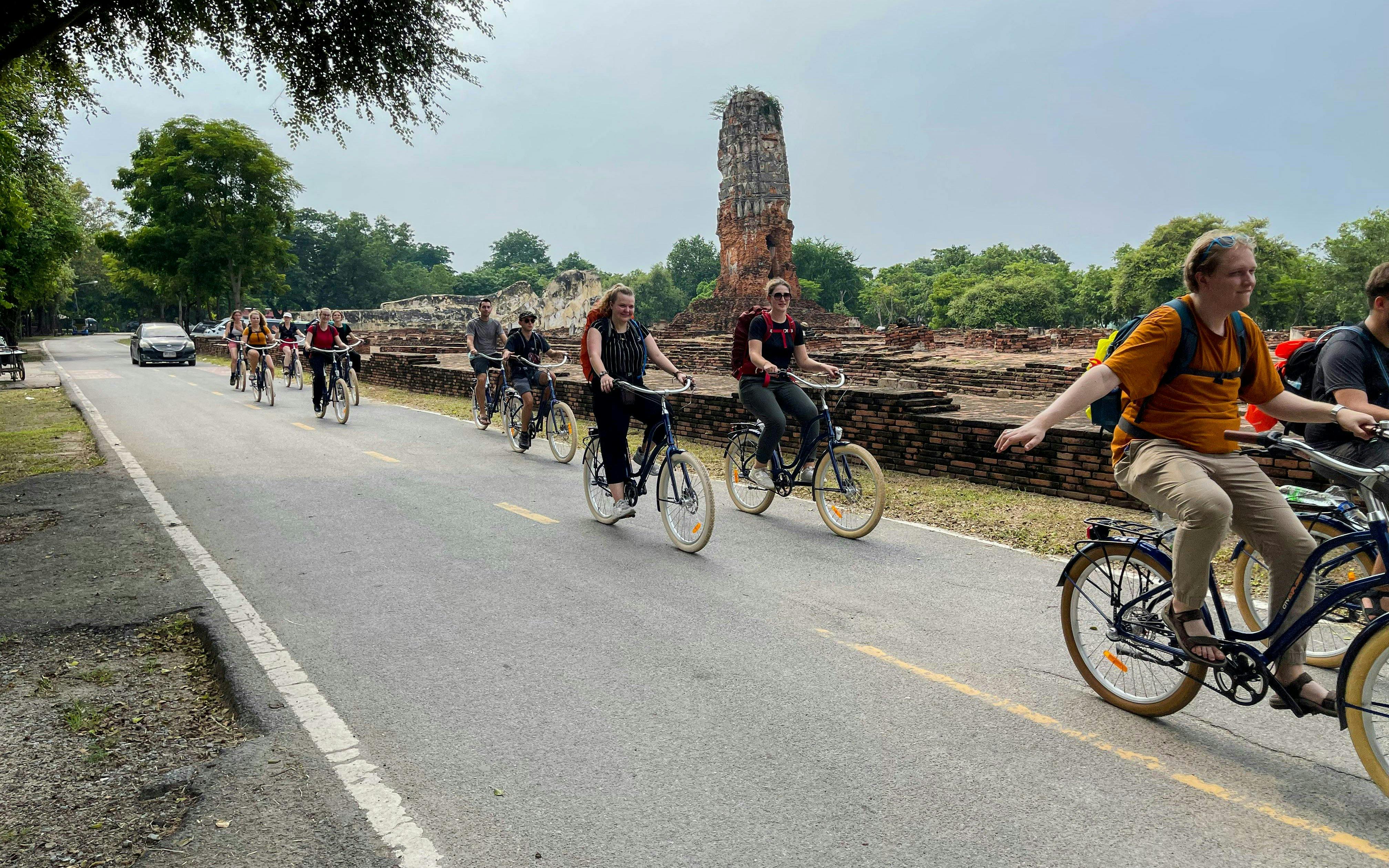 Cyclists riding past ancient ruins in Ayutthaya City, Thailand.