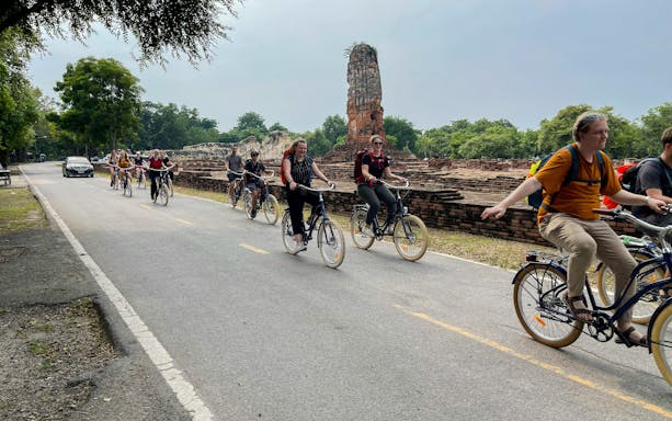Cyclists riding past ancient ruins in Ayutthaya City, Thailand.