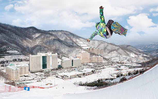 Snowboarder performing a jump at Vivaldi Ski Park, Seoul with mountains and resort in background.