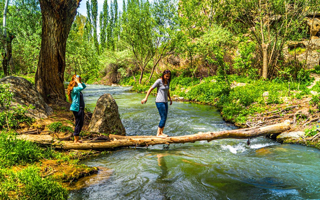 Trekking along a stream in Cappadocia's lush landscape during the Full-Day Green Tour.