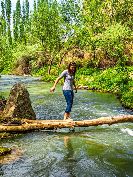 Trekking along a stream in Cappadocia's lush landscape during the Full-Day Green Tour.