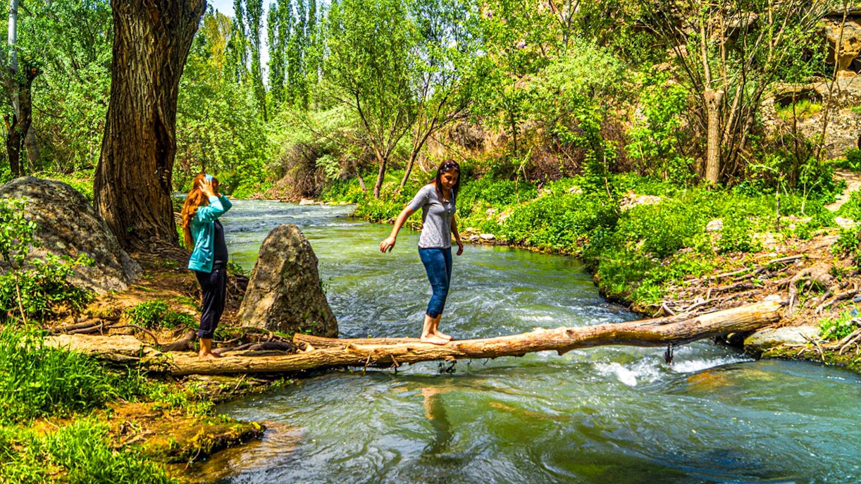 Trekking along a stream in Cappadocia's lush landscape during the Full-Day Green Tour.