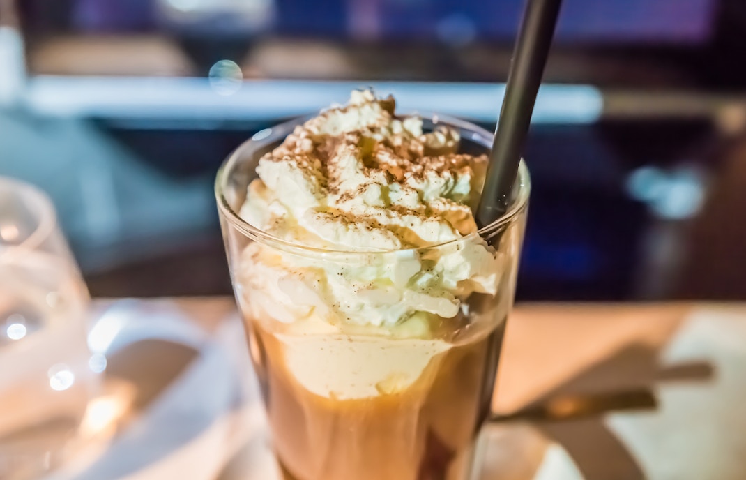 Iced Chocolatw topped with whipped cream and cocoa powder in a glass.