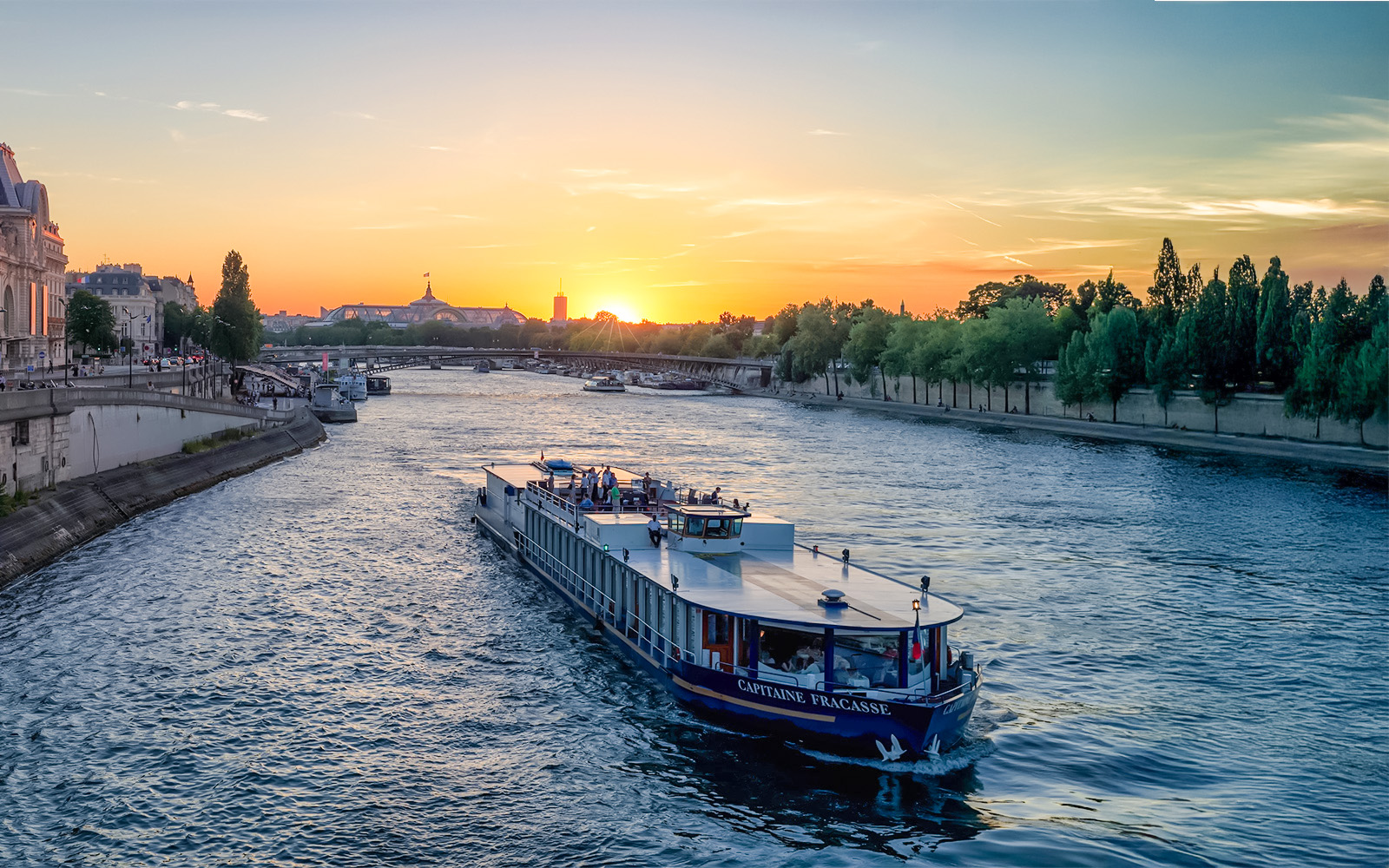 Seine River cruise boat at sunset with Eiffel Tower in Paris, Capitaine Fracasse dinner experience.