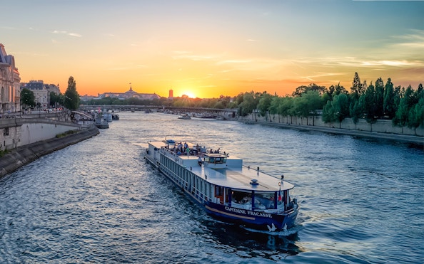 Seine River cruise boat at sunset with Eiffel Tower in Paris, Capitaine Fracasse dinner experience.