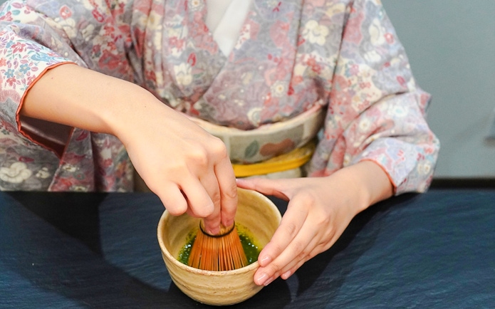 Whisking matcha powder in a bowl during a Japanese tea ceremony.
