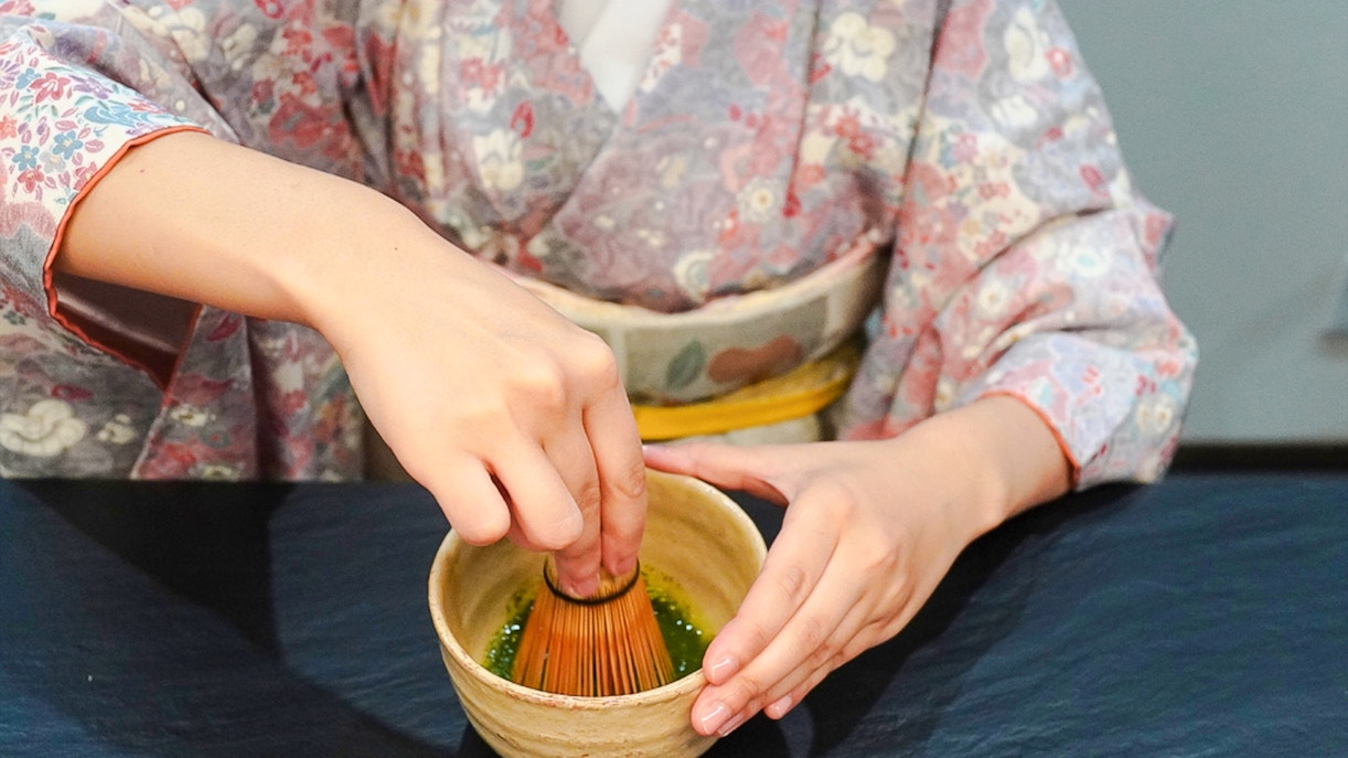 Whisking matcha powder in a bowl during a Japanese tea ceremony.
