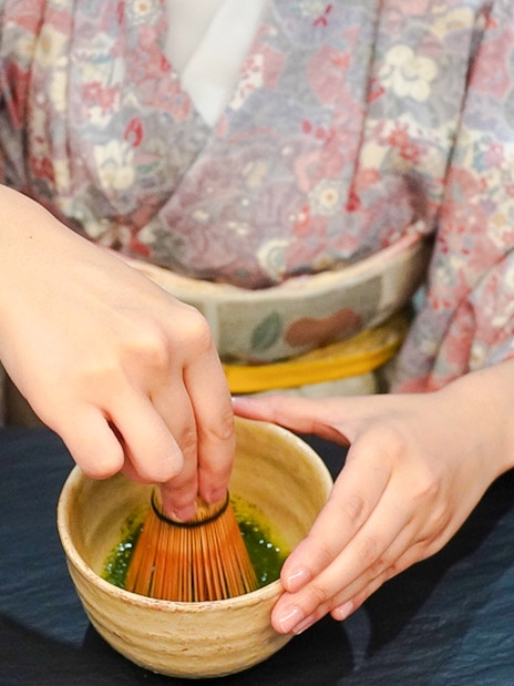 Whisking matcha powder in a bowl during a Japanese tea ceremony.