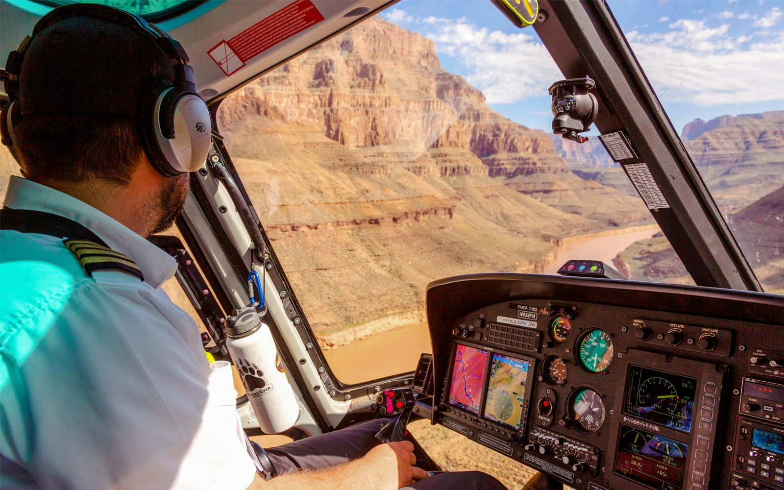 Helicopter pilot preparing for Grand Canyon West tour with airplane, helicopter landing, and pontoon boat ride.
