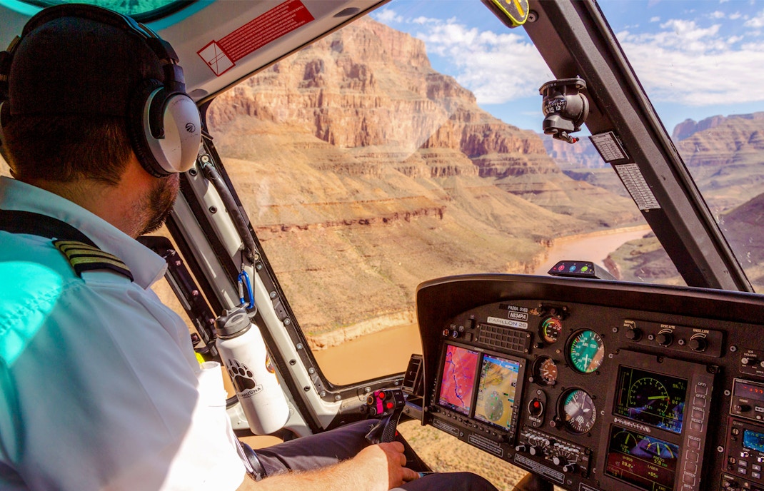 Helicopter pilot preparing for Grand Canyon West tour with airplane, helicopter landing, and pontoon boat ride.