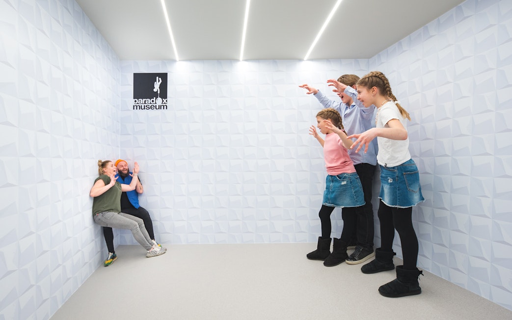 Visitors experiencing optical illusion at Paradox Museum exhibit.