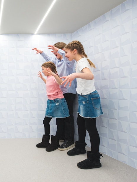 Visitors experiencing optical illusion at Paradox Museum exhibit.